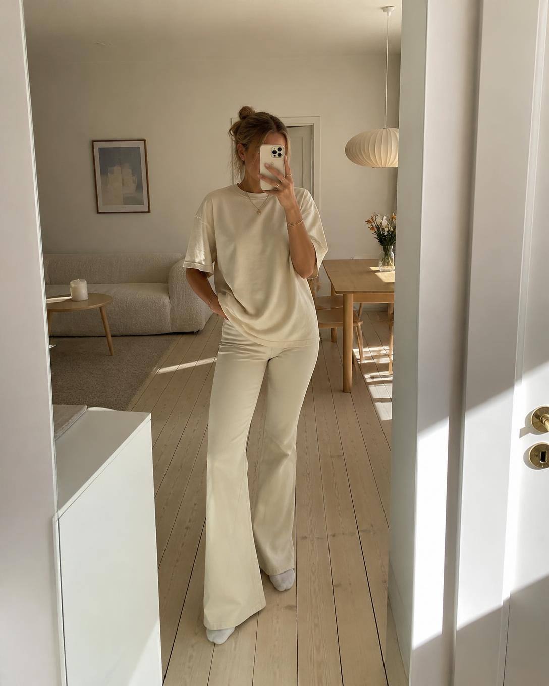 Creme flare-byxor och oversized tee hemma i morgonljus